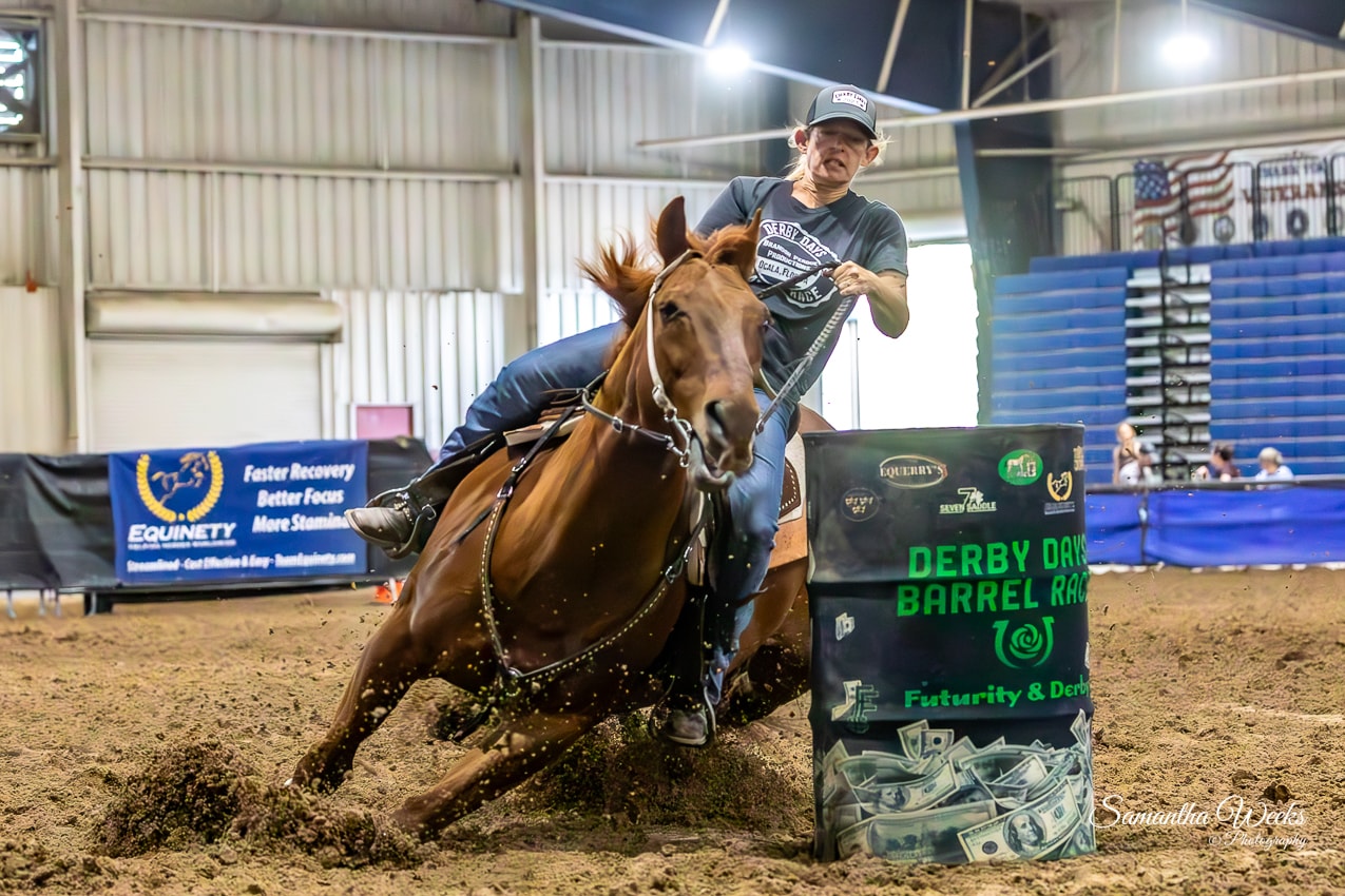 Rider in grey Derby Days shirt on chestnut horse rounding Derby Days Barrel Race drum
