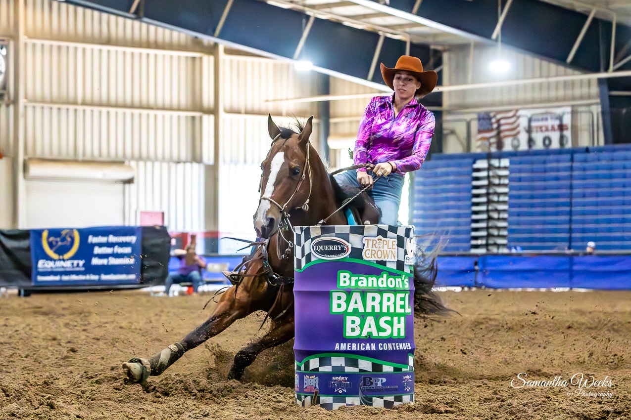 Cowgirl in purple metallic shirt on dark bay horse rounding Brandon's Barrel Bash drum