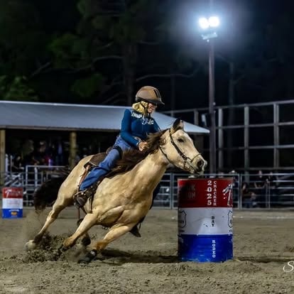 Rider in blue leaning into barrel racing turn