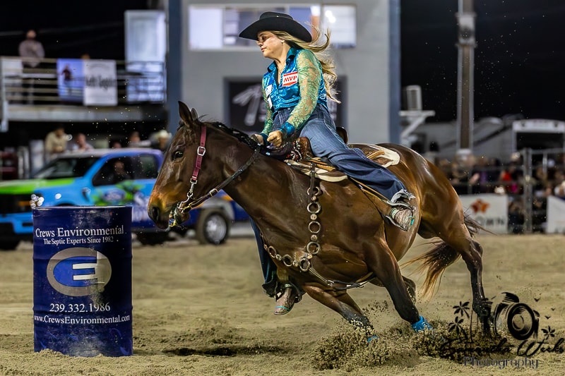 Rider in teal MVP shirt on bay horse turning barrel at speed