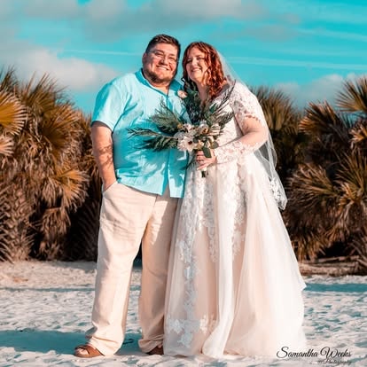 Couple smiling together at beach wedding with palm trees