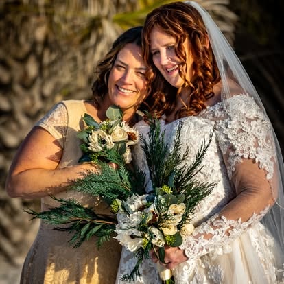 Two brides holding white flower bouquet on the beach
