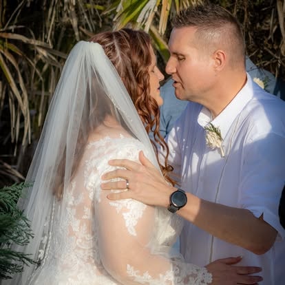 Bride and groom kissing with tropical foliage background