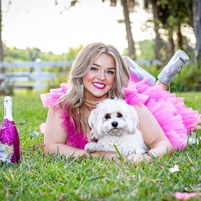 Woman in pink tutu holding white dog