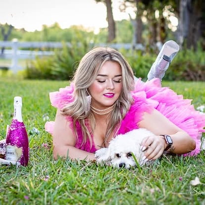 Woman in pink tutu with small dog and champagne
