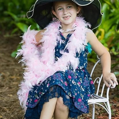 Child wearing pirate hat and pink feather boa