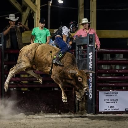 Bull rider bucking rodeo arena night