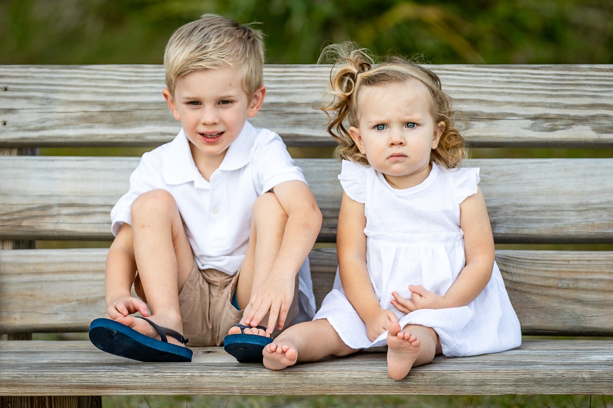 Two young children sitting on wooden bench