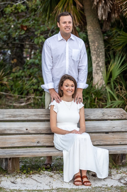 Couple posing on wooden bench by tropical foliage