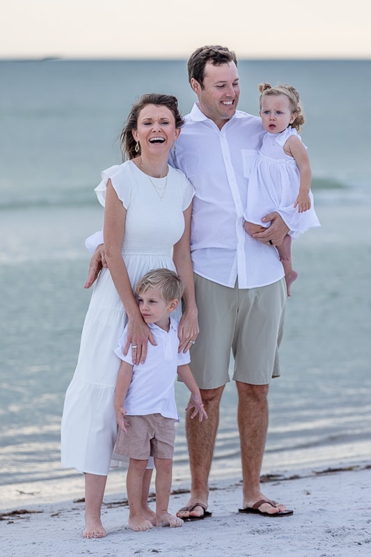Family of four standing on beach at sunset