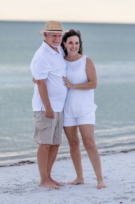 Older couple embracing on beach at sunset