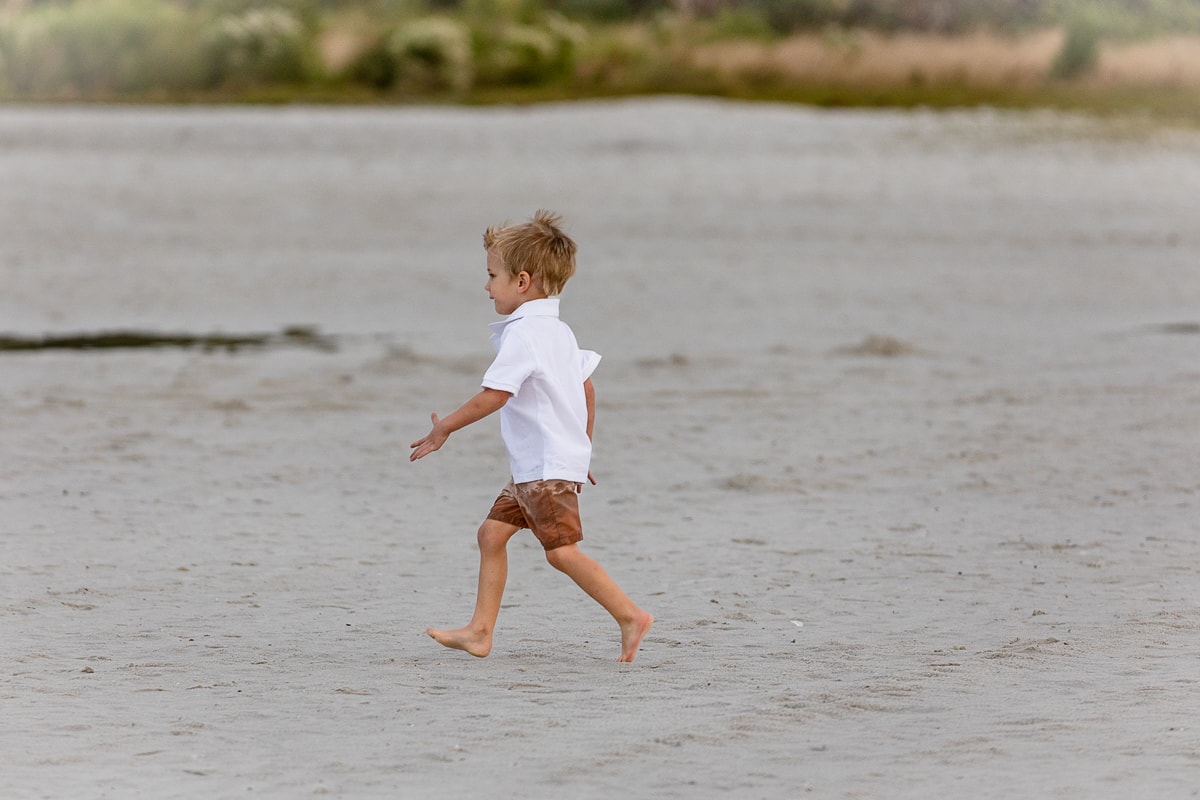 Young boy running barefoot on the beach