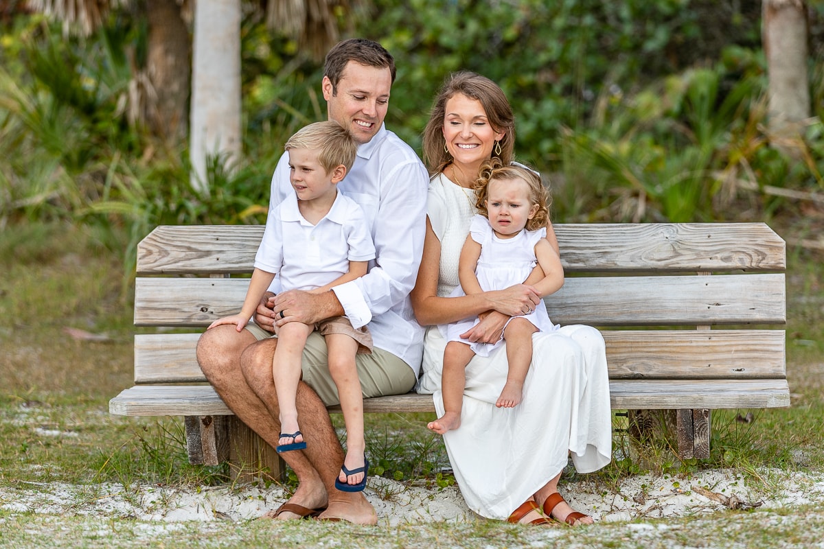 Family of four sitting on beach bench