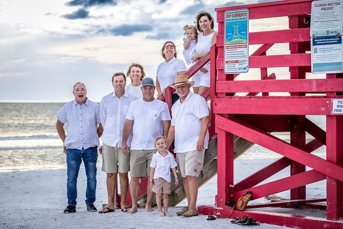Extended family posing at red lifeguard stand on beach