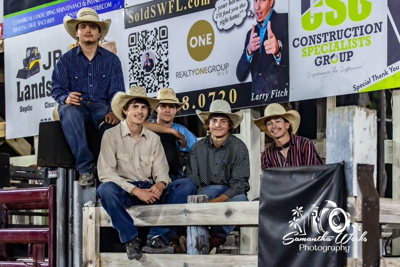 Five young cowboys in straw hats sitting on arena fence at 65th Cracker Day Rodeo