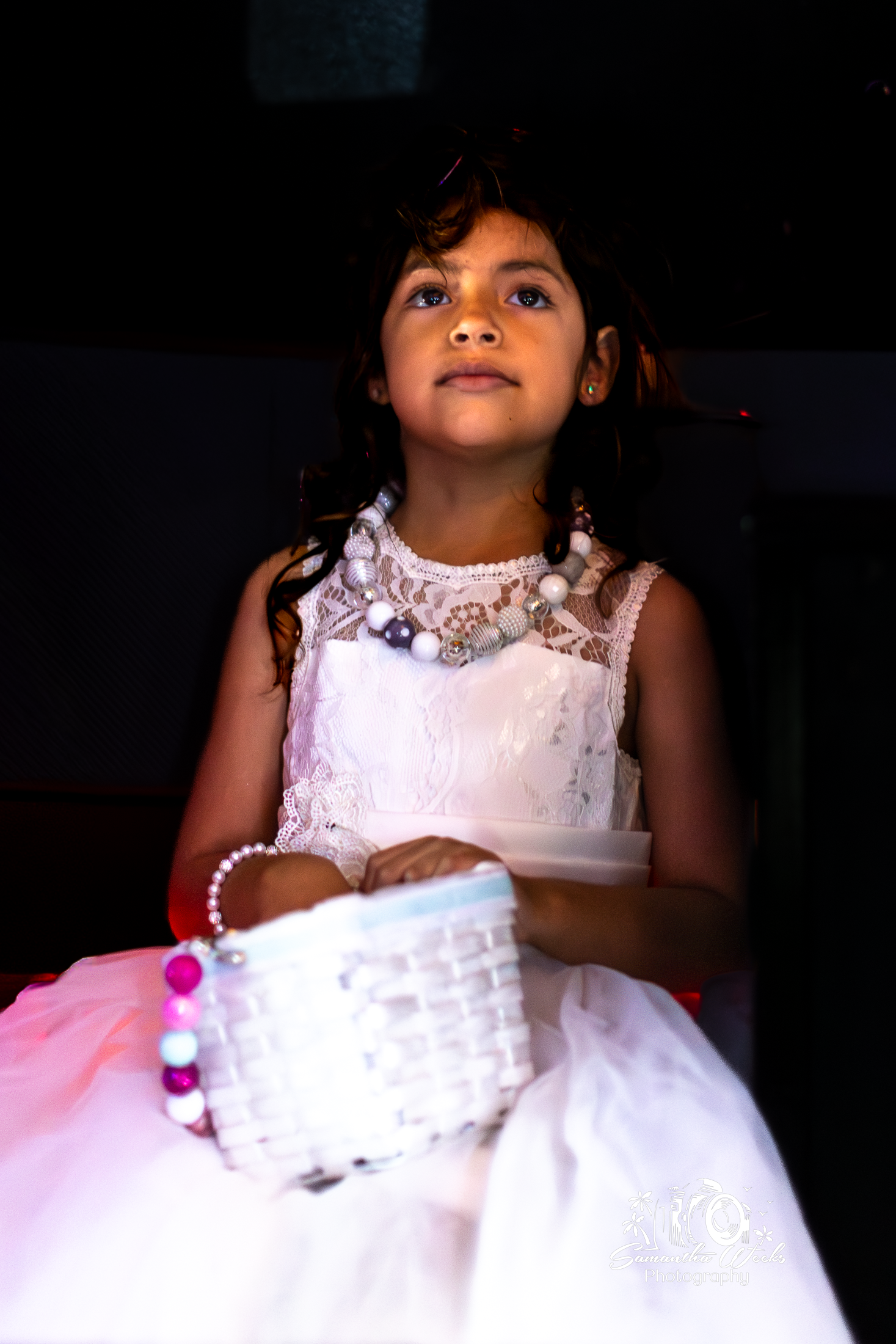 Young girl in white lace dress looking upward